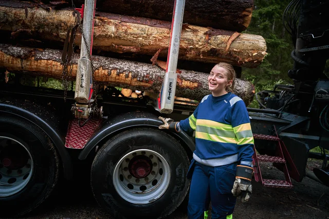 Timber truck driver wearing a blue high-visibility jacket and blue work trousers from Fristads.