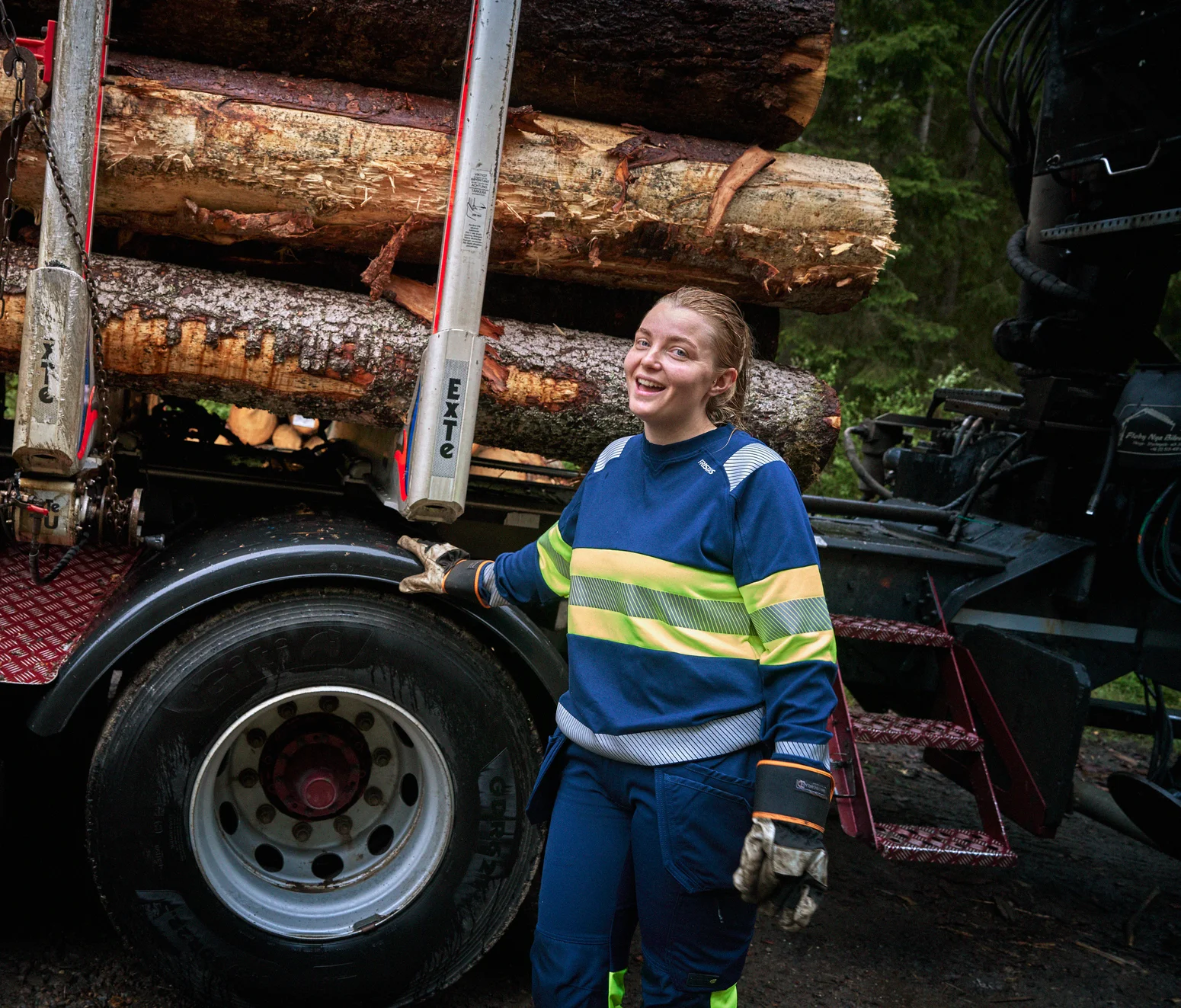 Timber truck driver wearing a blue high-visibility jacket and blue work trousers from Fristads